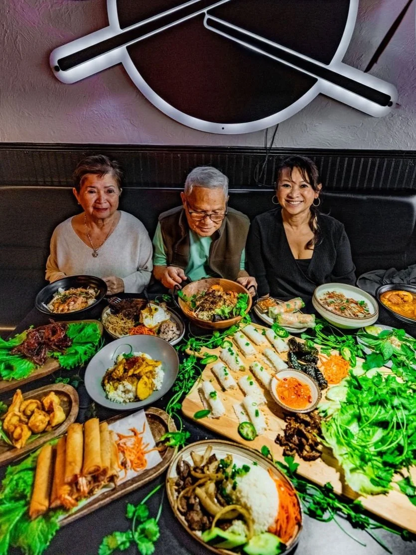 Family gathered around a full table of Vietnamese dishes at Mia's